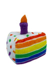 Rainbow striped cakep plush slice with purple candle on top close up